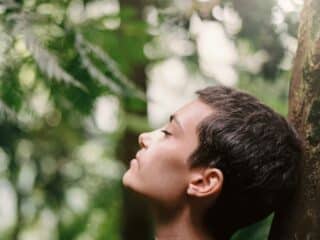 boy leaning back on tree