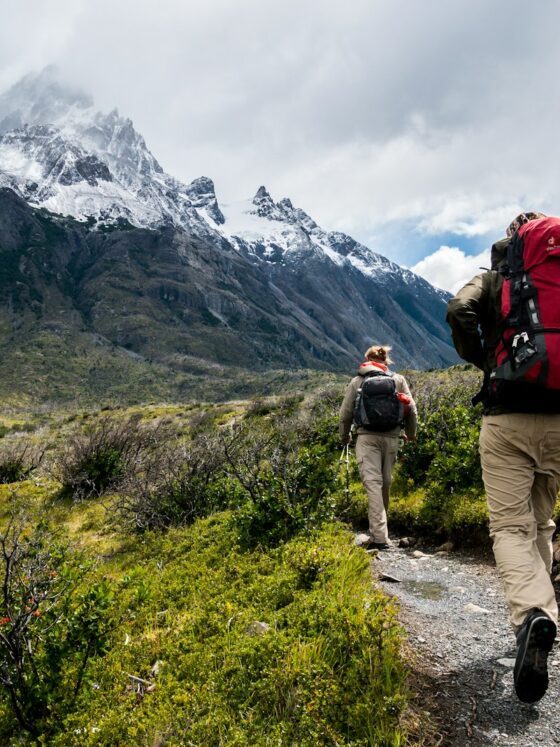 two person walking towards mountain covered with snow
