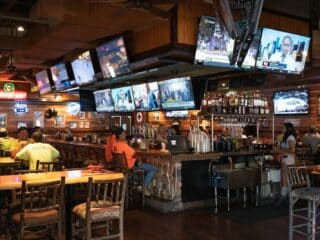 The Rise of Social Sports Bars as Community Hubs a group of people sitting at a bar watching tvs